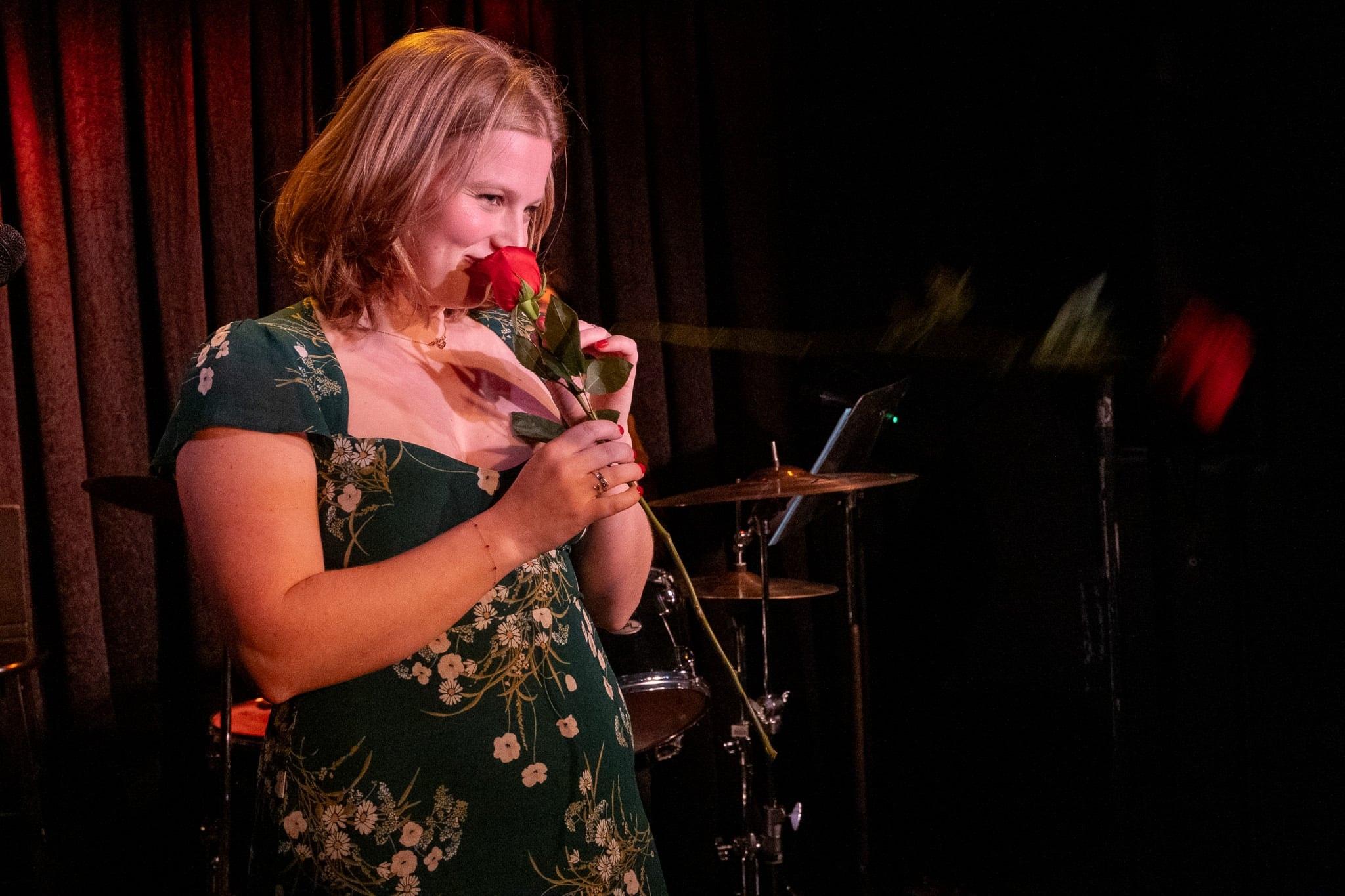 The singer smelling a single rose, eyes closed.