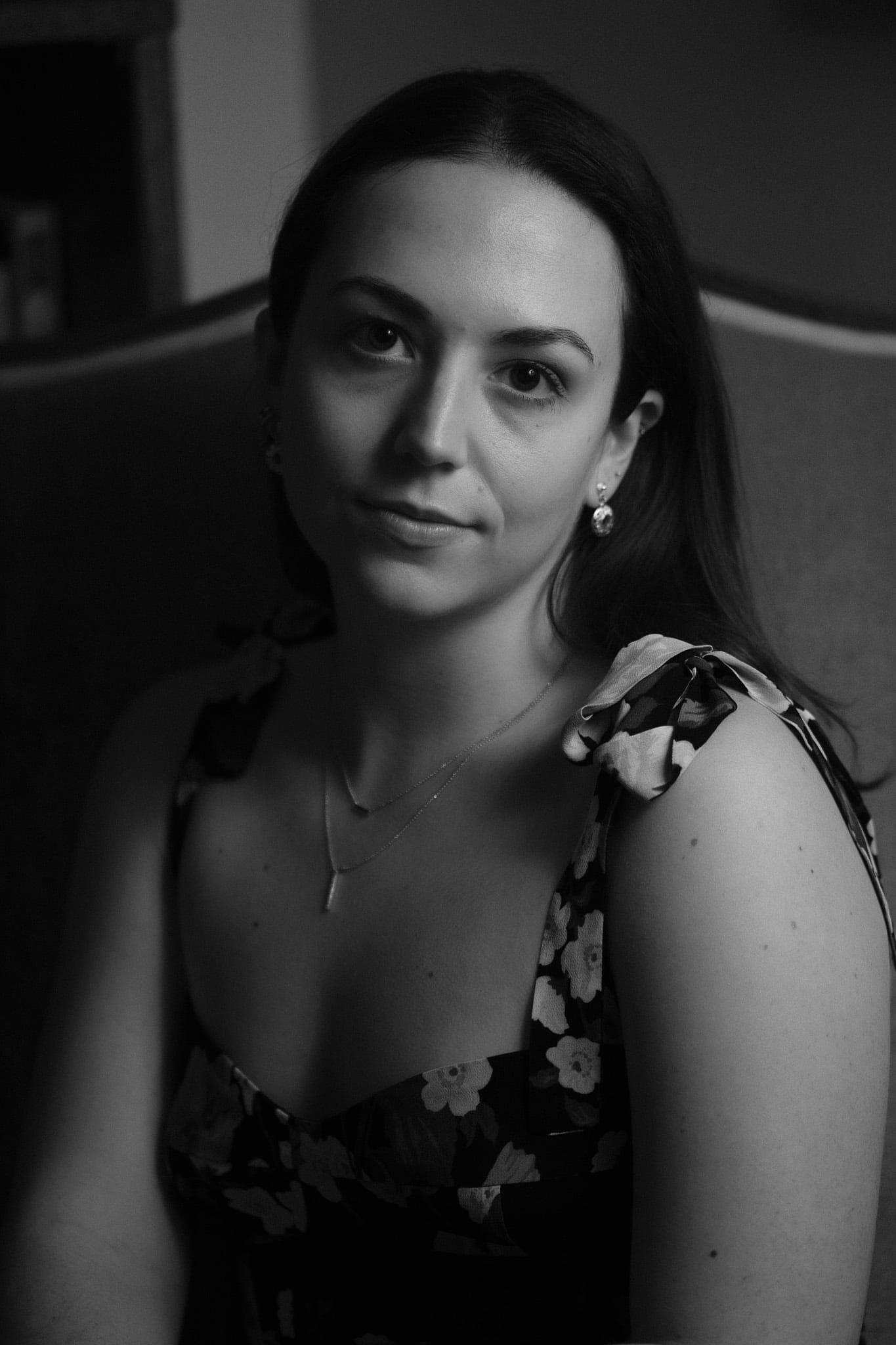 A woman in a floral dress, head tilted, a slight smile, in black and white.