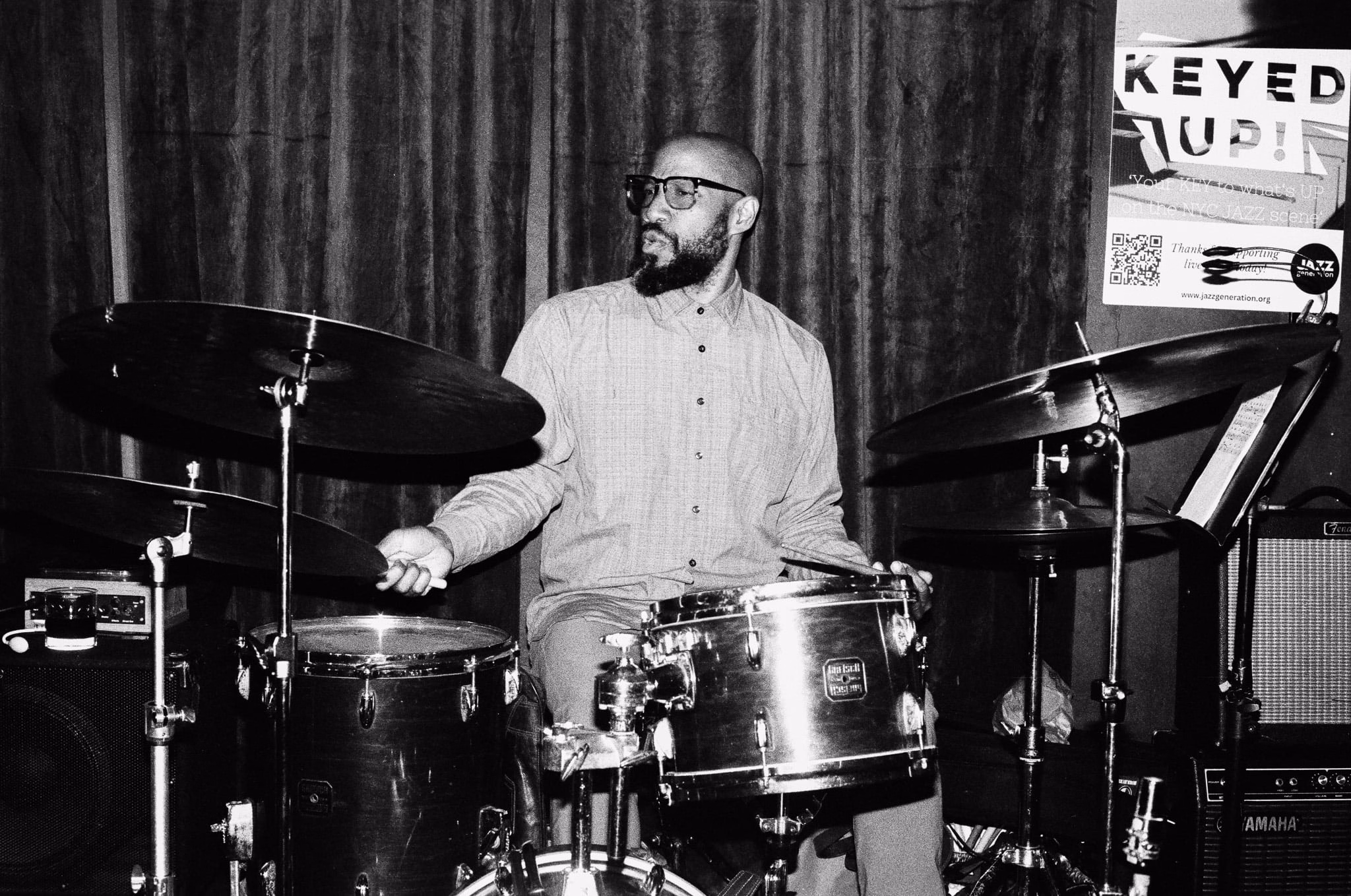 A drummer mid-song, in black and white.