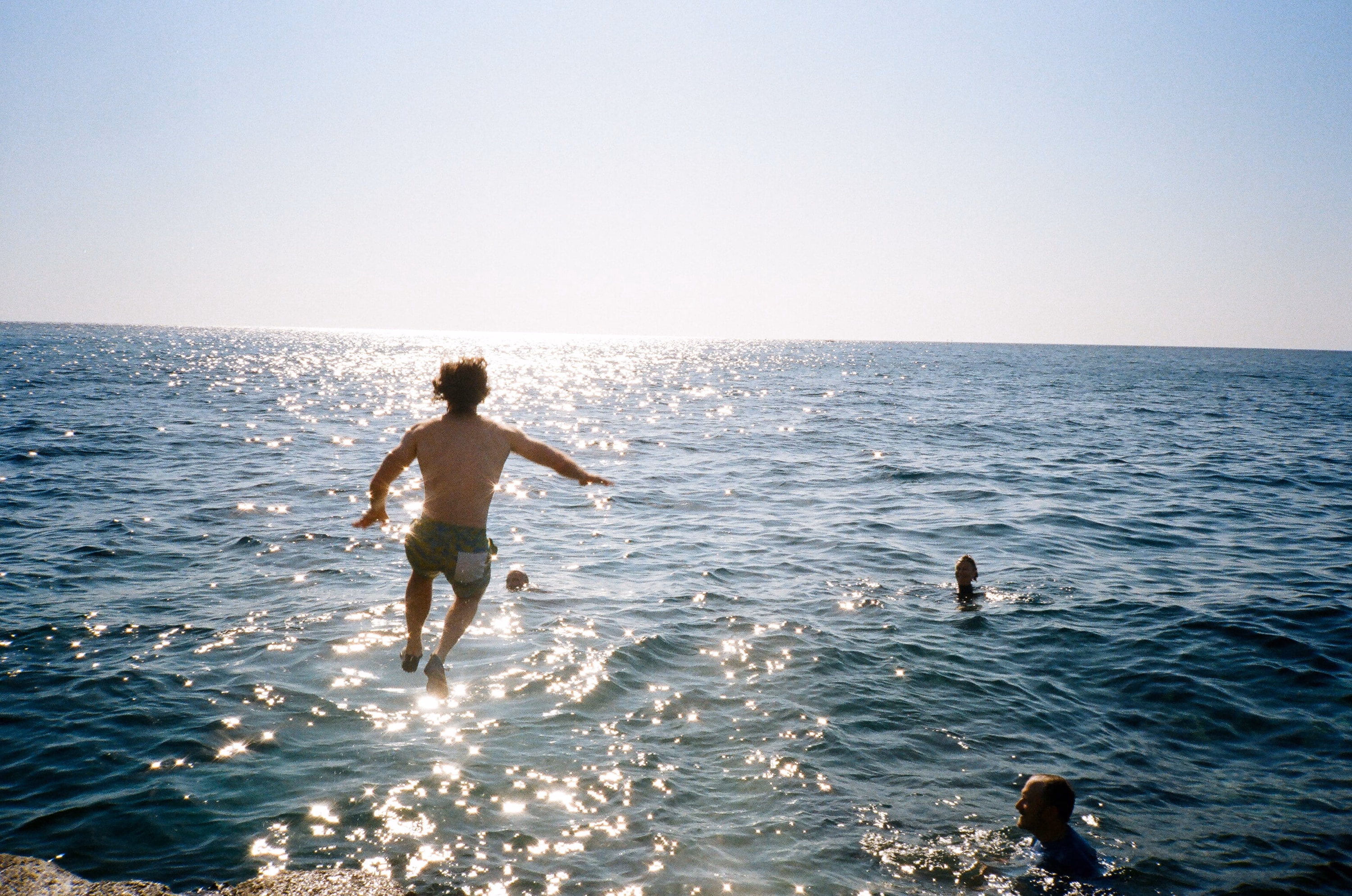 A man leaping into a glittering sea.