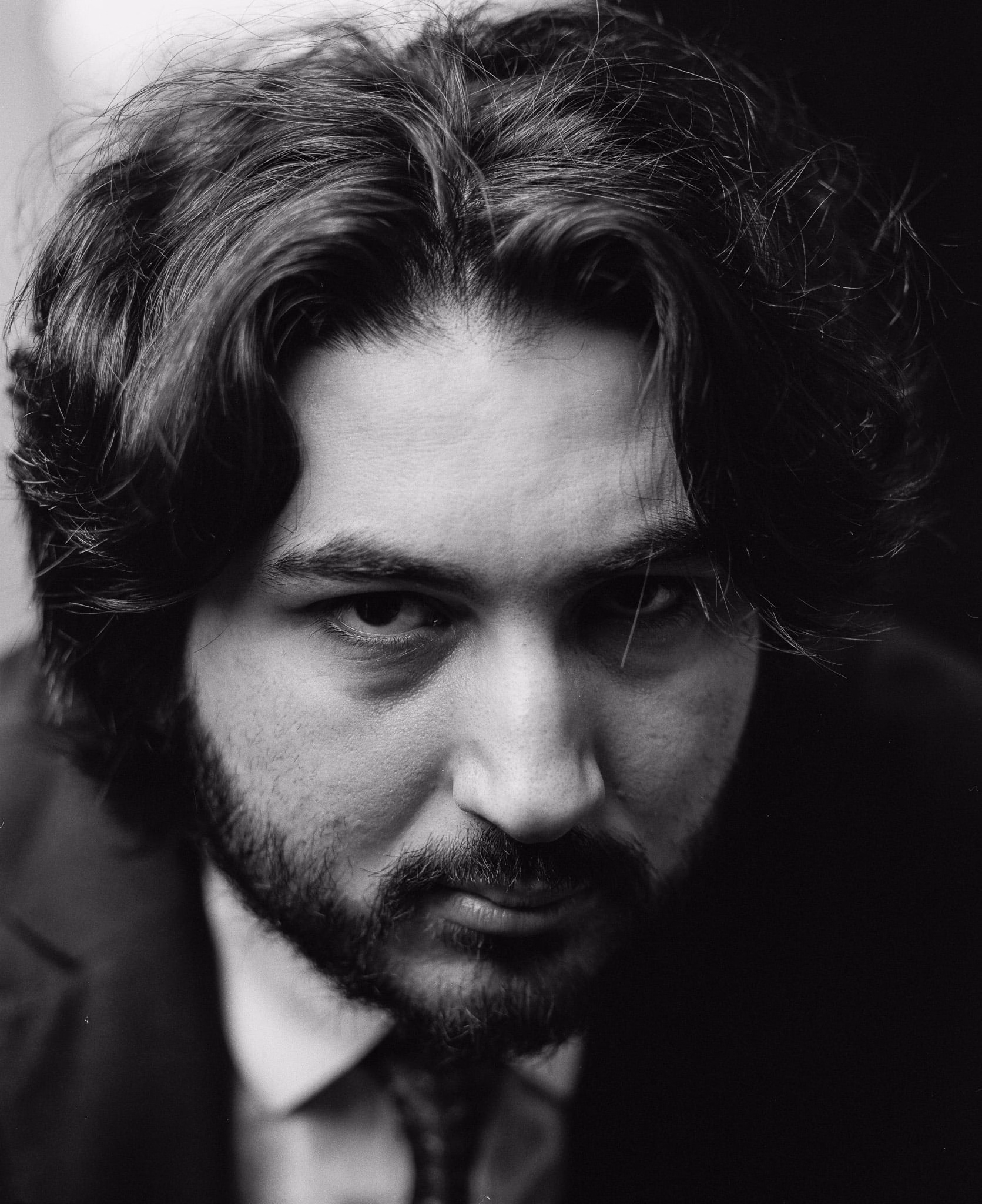 A black-and-white film portrait of a bearded man in a suit.