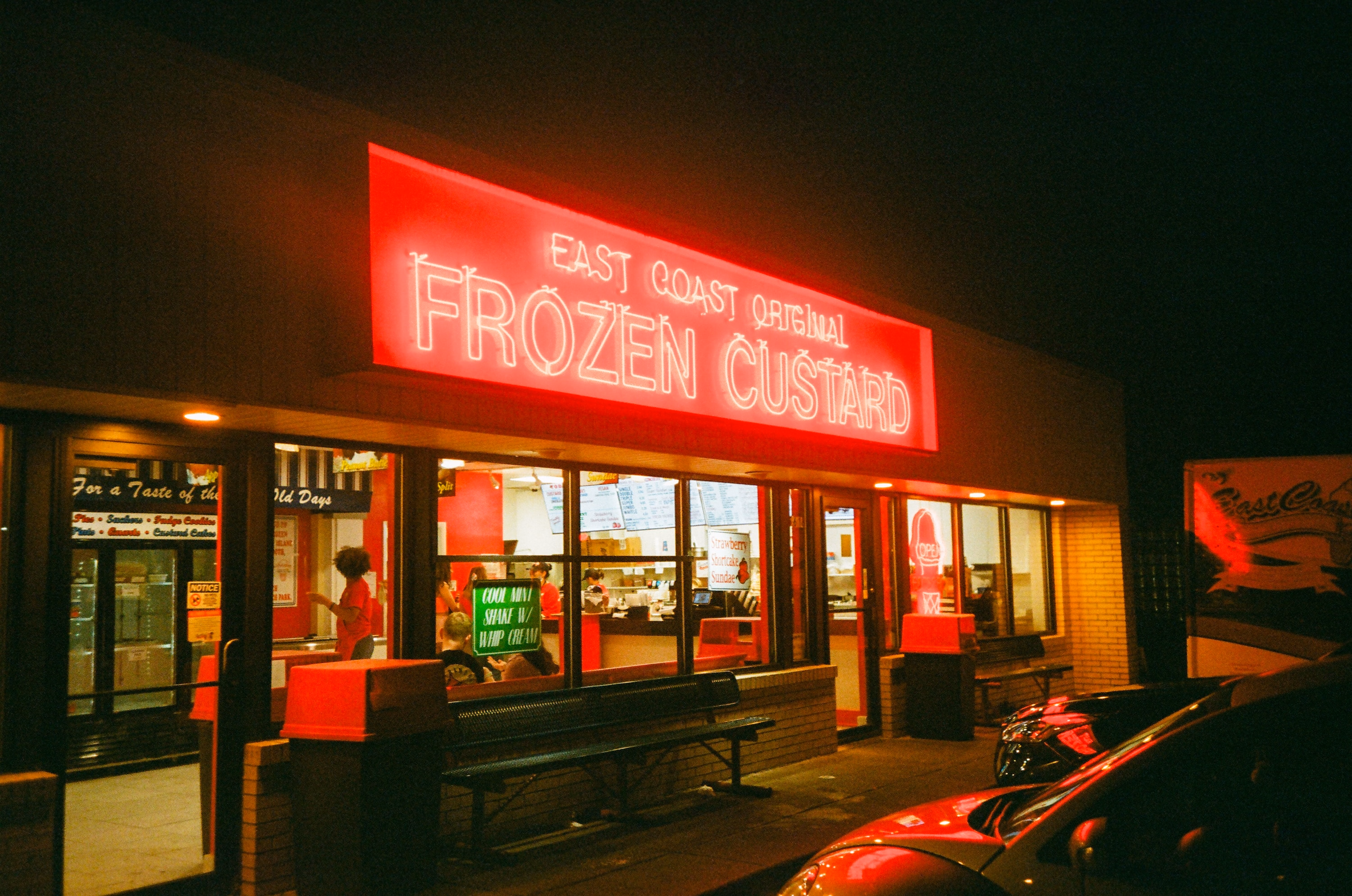 A frozen custard stand at night under red neon.